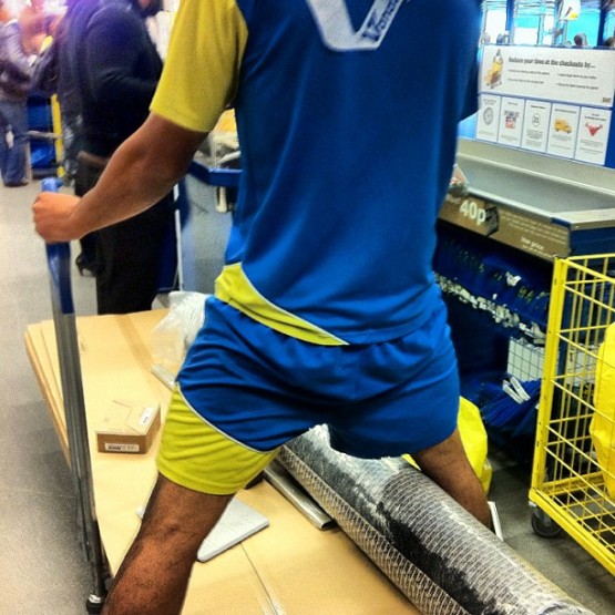 Sportily dressed man in Swedish colours astride his Ikea shopping cart